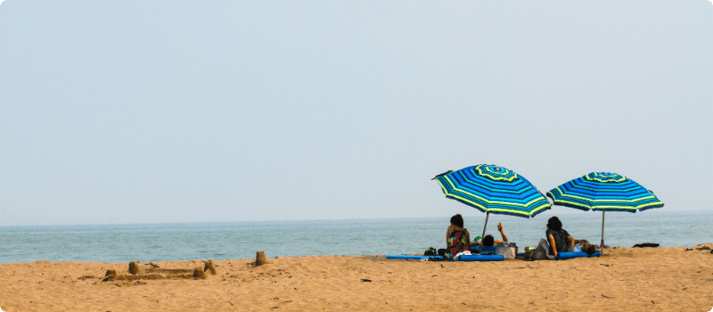 People sitting under large umbrellas on the beach.