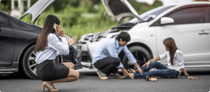 Person helping an accident victim while another calls for help.