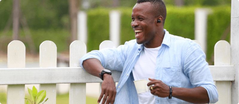 Happy person talking on the phone while leaning on his fence. 