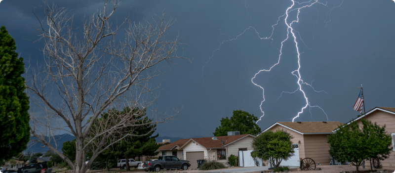 Houses with lightning striking in the background.