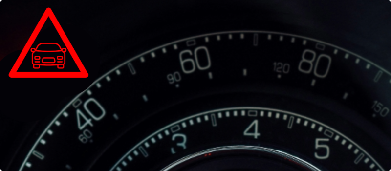 A close-up of a car's dashboard with the distance warning light illuminated.