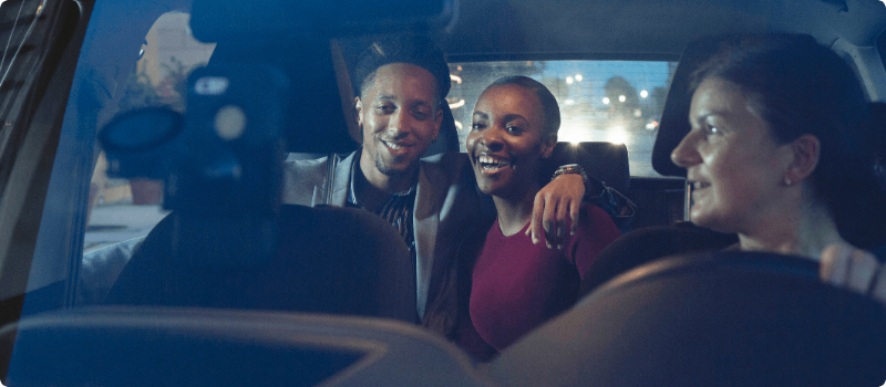 A rideshare driver driving a happy couple.