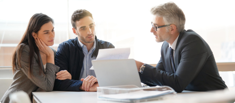 An insurance agent showing a document to an interested couple.