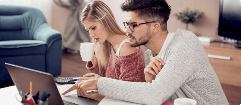 Couple sitting at a table with a laptop.