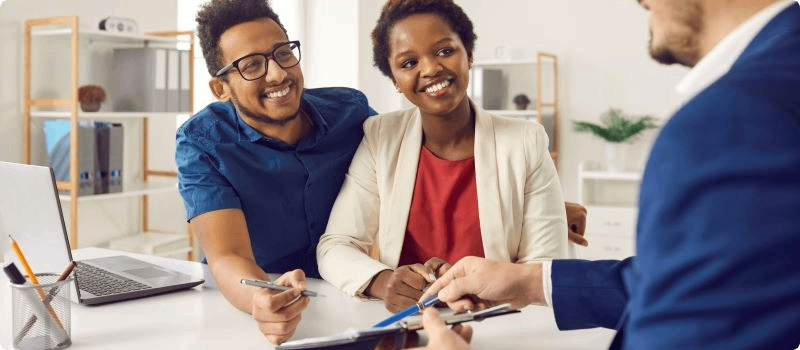 Happy couple reviewing insurance policy with an agent.
