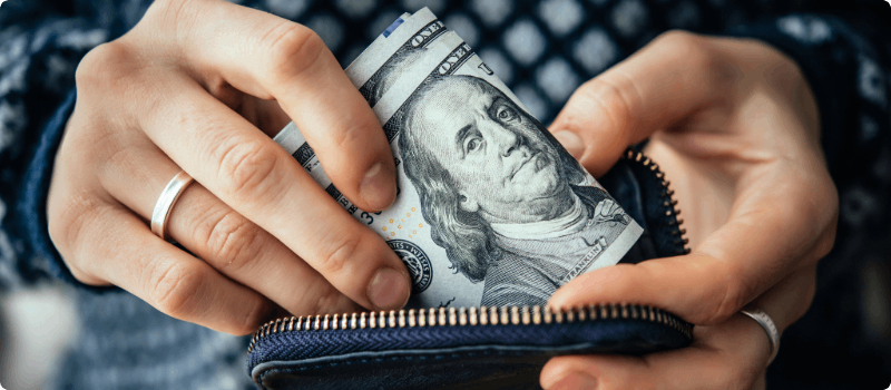 Person placing money into her wallet.