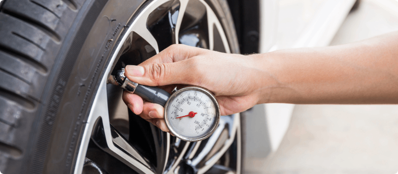 Person checking their car's tire pressure.
