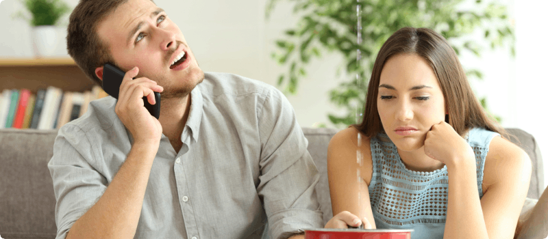A couple sitting under a leaking ceiling.