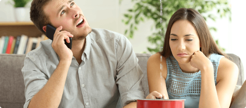 A couple sitting under a leaking ceiling.