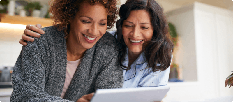 Two happy people looking at a computer tablet.