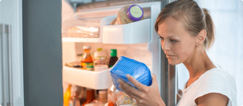 Person checking food in her fridge.