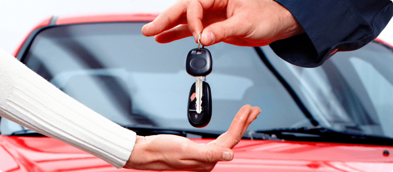 Salesperson handing car keys to a buyer.