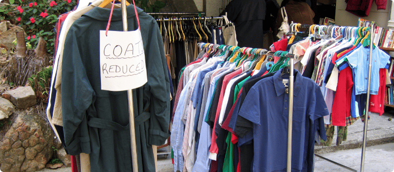 Racks of clothes laid out in a garage sale.
