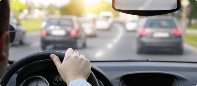 Person driving on a busy road on a sunny day. 
