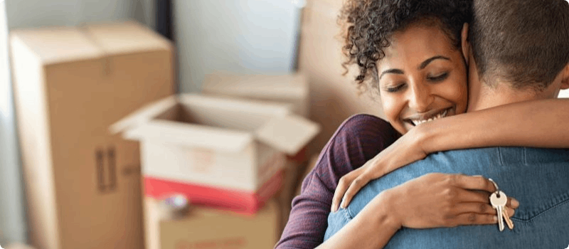 Couple embracing in their new home. 