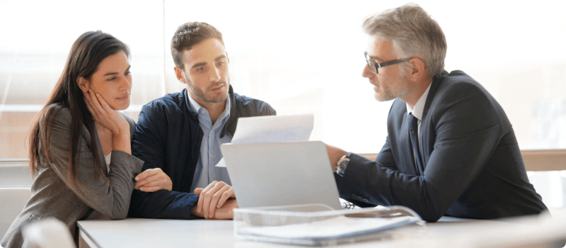 Couple reviewing a contract with a real estate agent. 