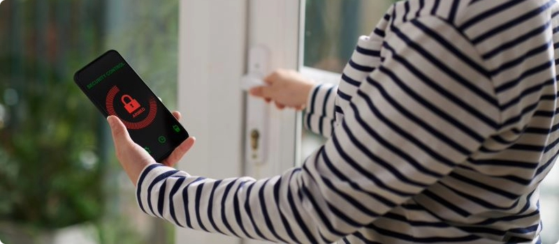A homeowner using their smart home technology to ensure their home's doors are locked.