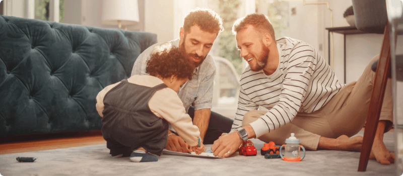 A happy couple playing with their infant in their living room.
