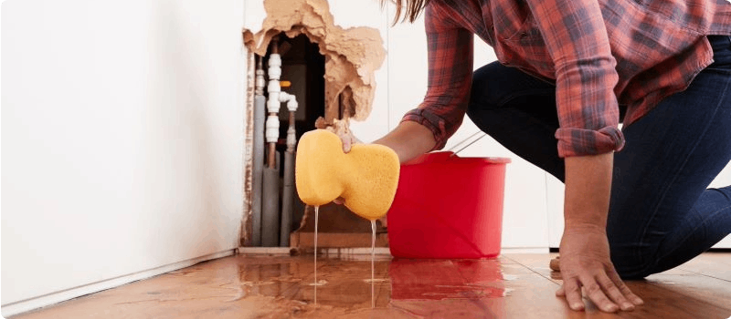 Person cleaning broken pipe flooding.