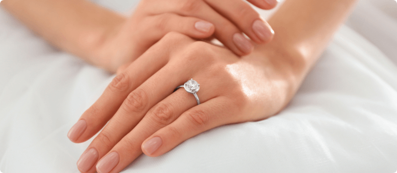 Bride with folded hands on her lap, showcasing her wedding ring. 