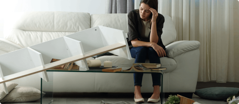 Person sitting on her couch after realizing she's been robbed.