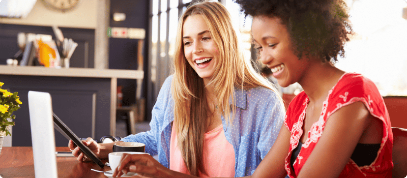 Two happy people working together at a table on a laptop.