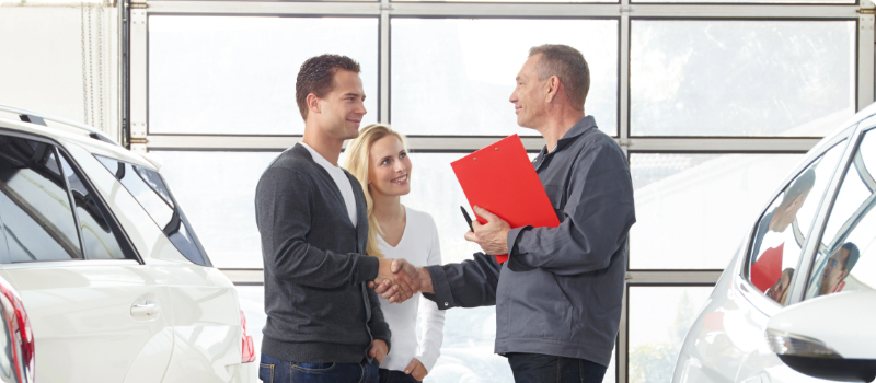 A couple shaking hands with an auto dealer.