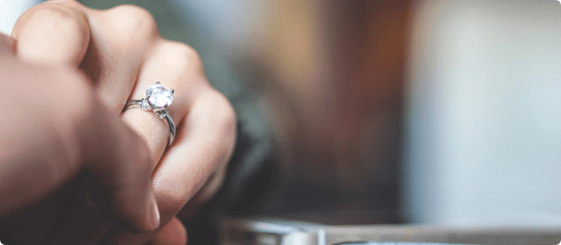 Partners holding hands, showcasing a diamond engagement ring.