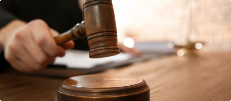 A close-up of a judge striking their gavel on their desk.