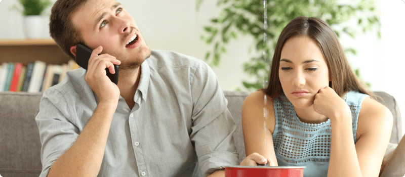 Two people sitting under their leaking roof.
