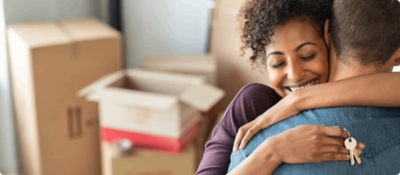 Happy couple hugging while holding the keys to their new home. 