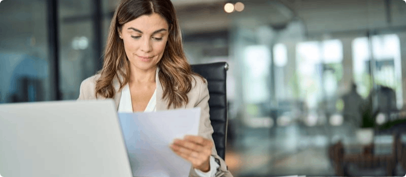 Person sitting at a laptop while reviewing a document.