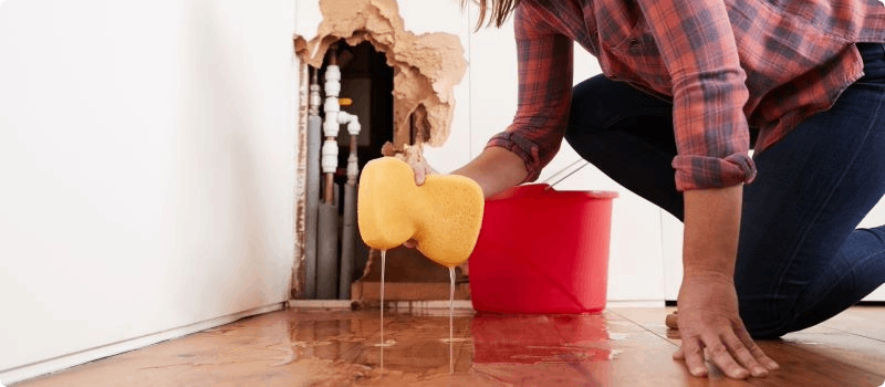 Person cleaning flooding from broken pipe, water leak. 