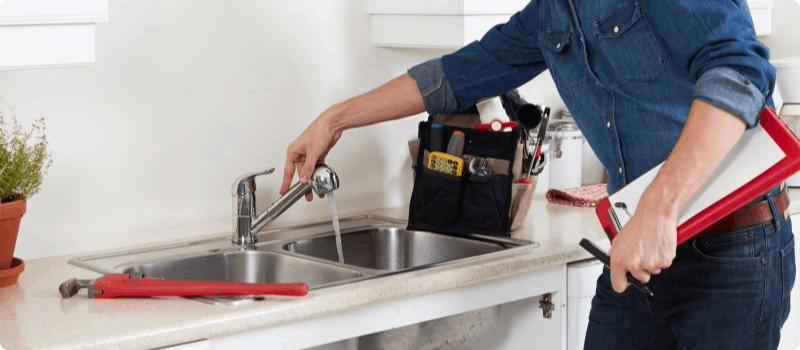 Maintenance person fixing leaking kitchen sink.