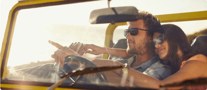 A couple embracing while going for a coastal drive in a Jeep.