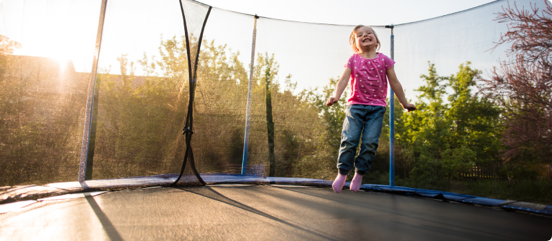 Smiling kid bouncing on trampoline.