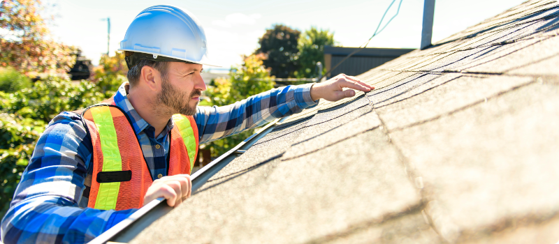 a man inspecting a home's roof