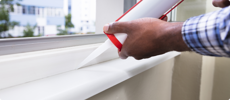 applying caulk to a drafty window