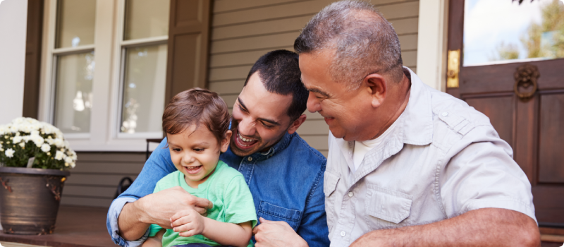 Male Multi Generation Family Sitting On Steps in Front Of House