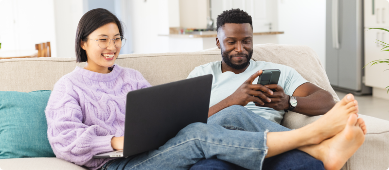 a couple relaxing on the could with a phone and laptop