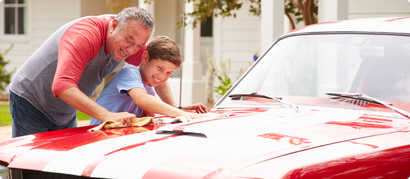 a grandfather and grandson washing a classic car