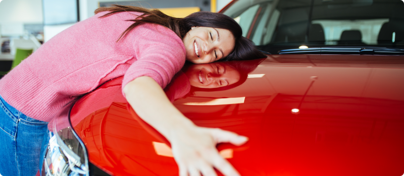 a happy woman hugging her new car