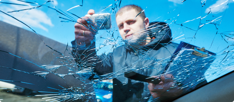 Insurance agent taking pictures and recording car damage on claim form.