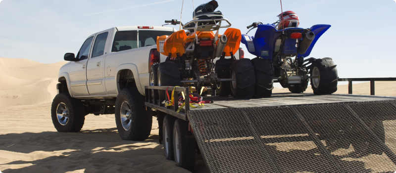 a truck pulling a trailer with ATVs on it