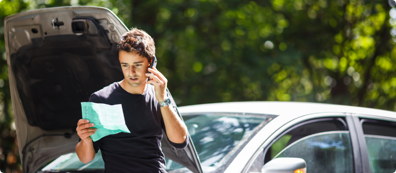 a man looking at a document outside his car