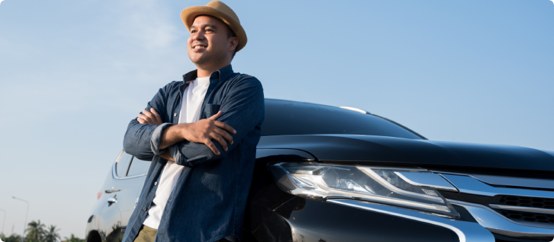 Young man leaning against his new car