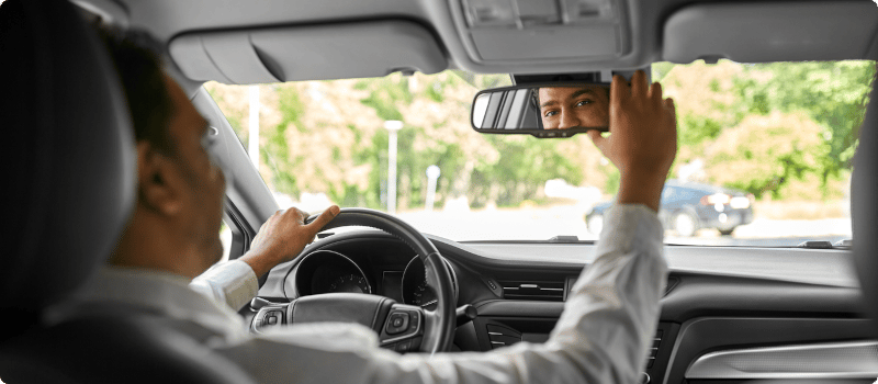 a person adjusting their rear view mirror