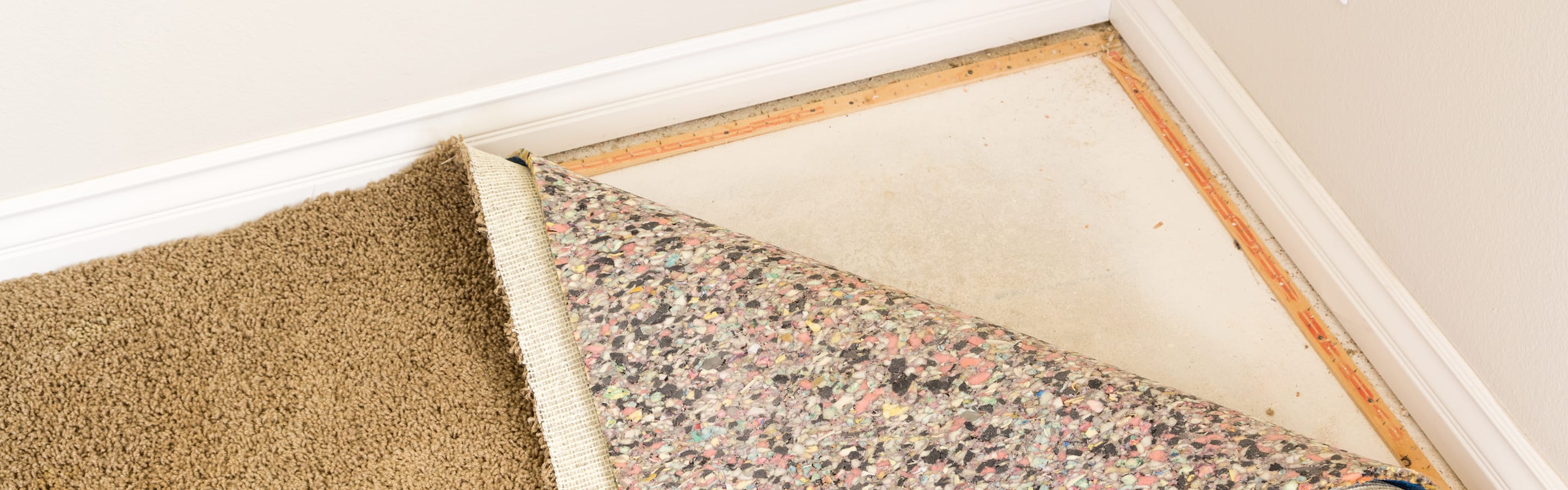 Wet carpet and padding being removed from a flooded basement floor.