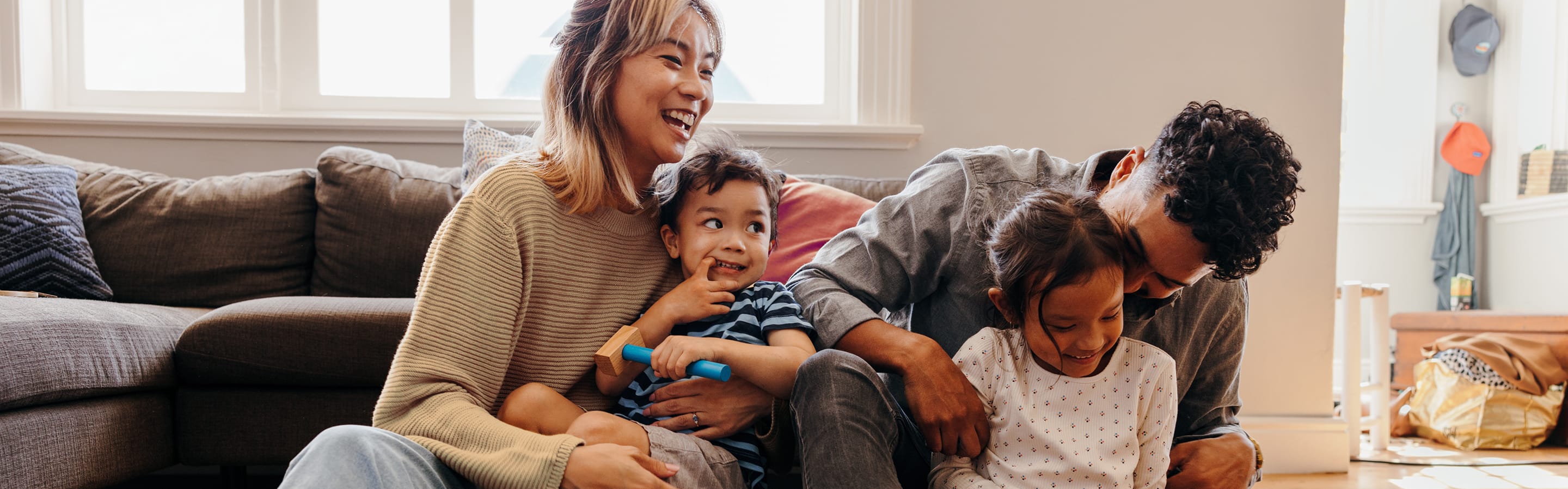 Family laughing and playing together on the living room floor.