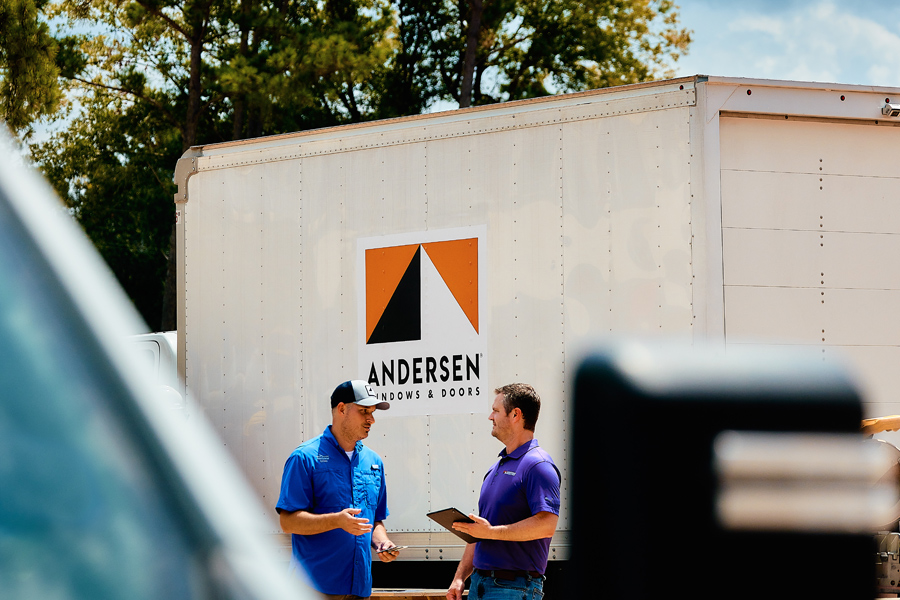 Two men chatting in front of an Andersen Windows truck